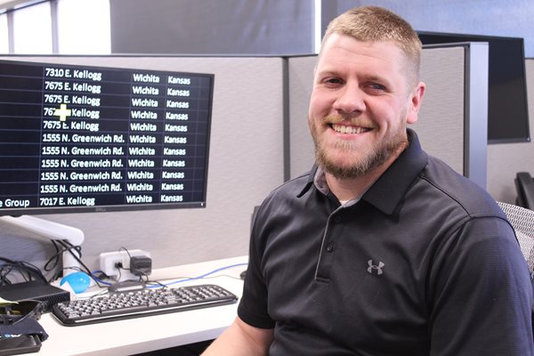 Kyle Shaults smiling at his desk and computer in the Envision Workforce Innovation Center call center