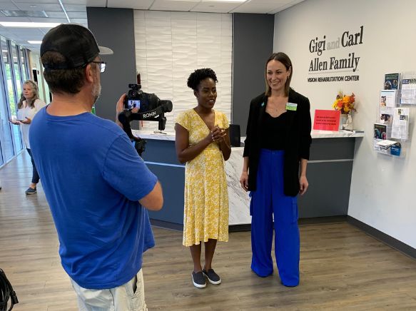 Sarah Kephart talking into a camera and smiling, standing inside Envision Dallas lobby.