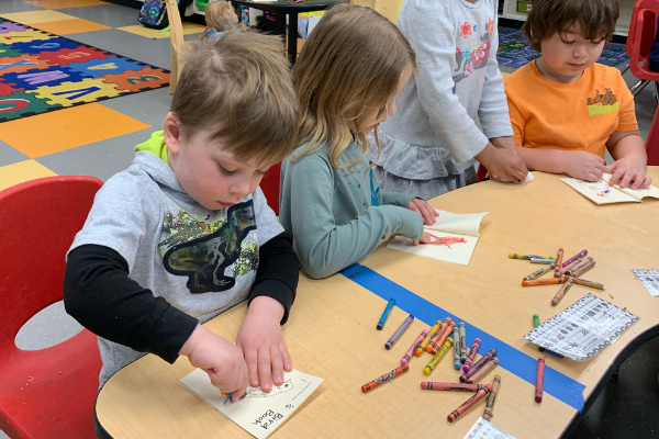 a group of students at a table coloring pictures of birds