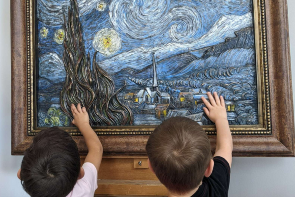 Two kids touching a piece of tactile art.