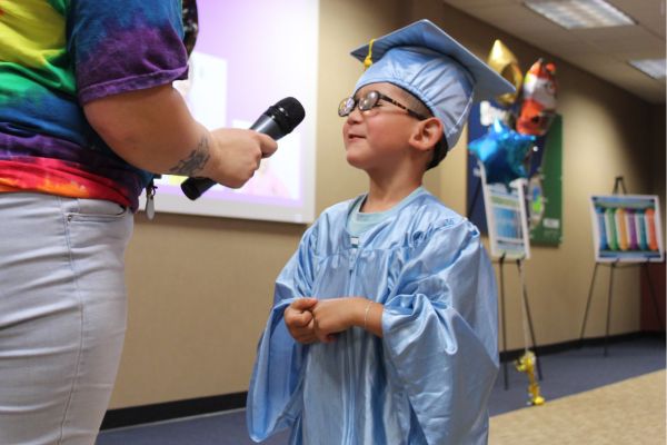 Carter in his graduation cap and gown speaking into a microphone and telling the crowd what he wants to be when he grows up. 