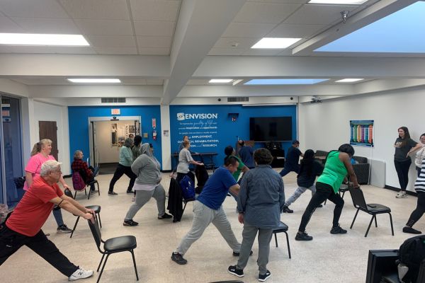 Ph.D. Students at Envision Dallas Focus Capstone Projects On Accessibility Envision Dallas yoga participants stretching during the yoga class.