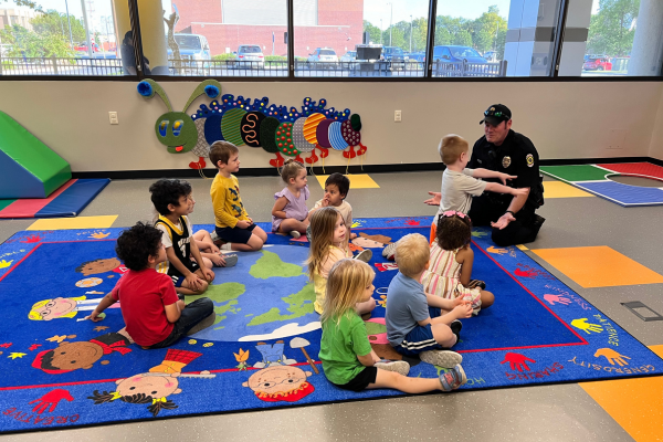 Officer Byers sitting on the carpet talking to a group of kids.
