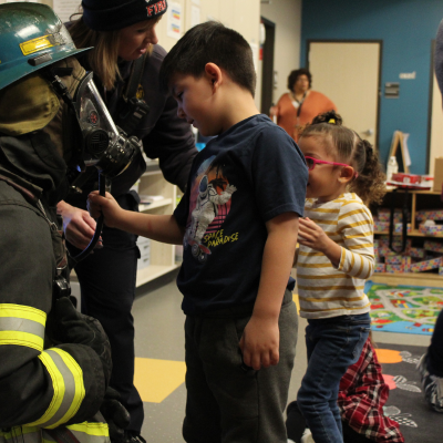 A boy touching the firefighter's breathing apparatus.