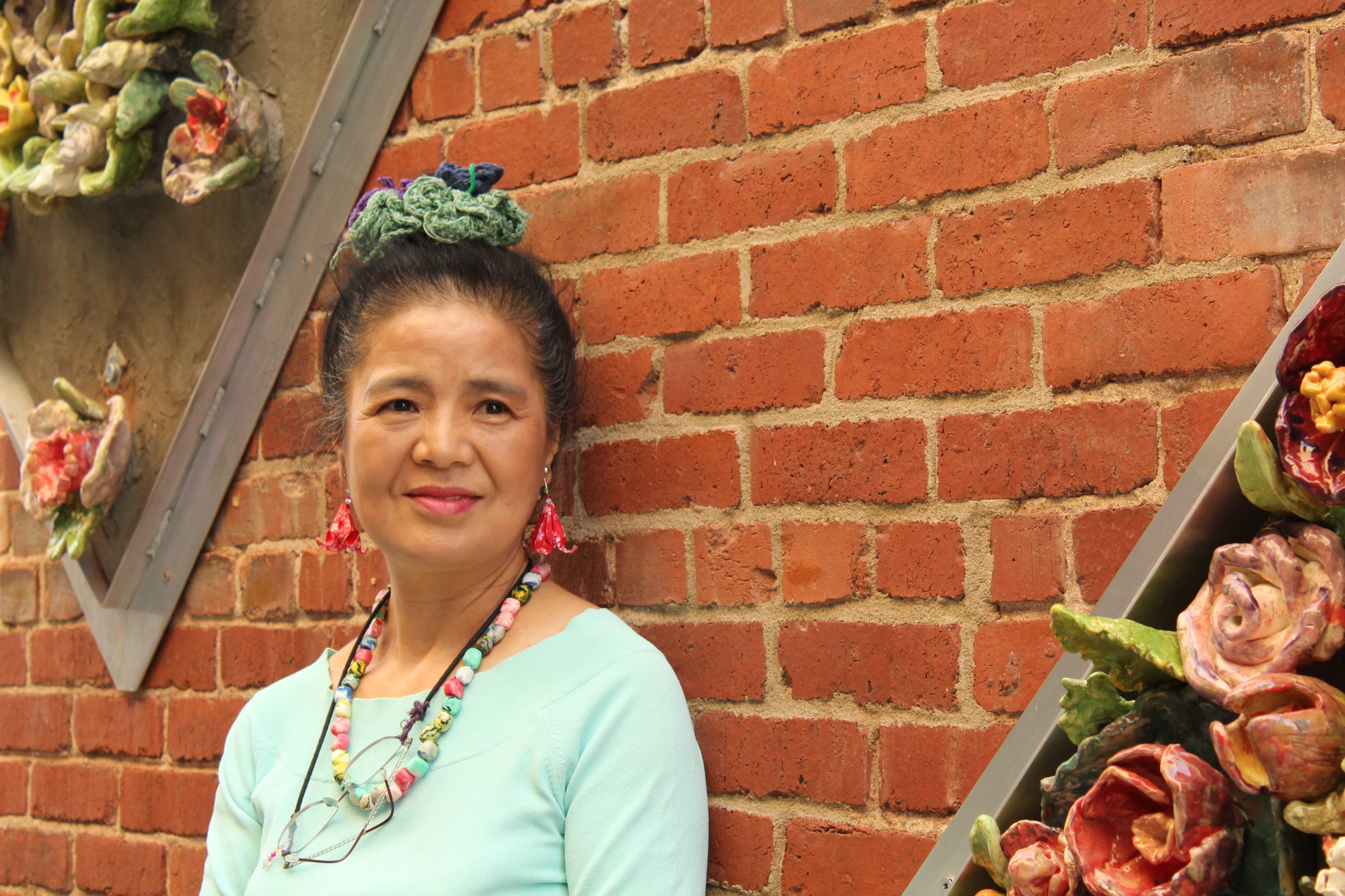 Tomiyo Tajiri in Gallery Alley in Wichita, Kansas standing next to her ceramic flower art displays