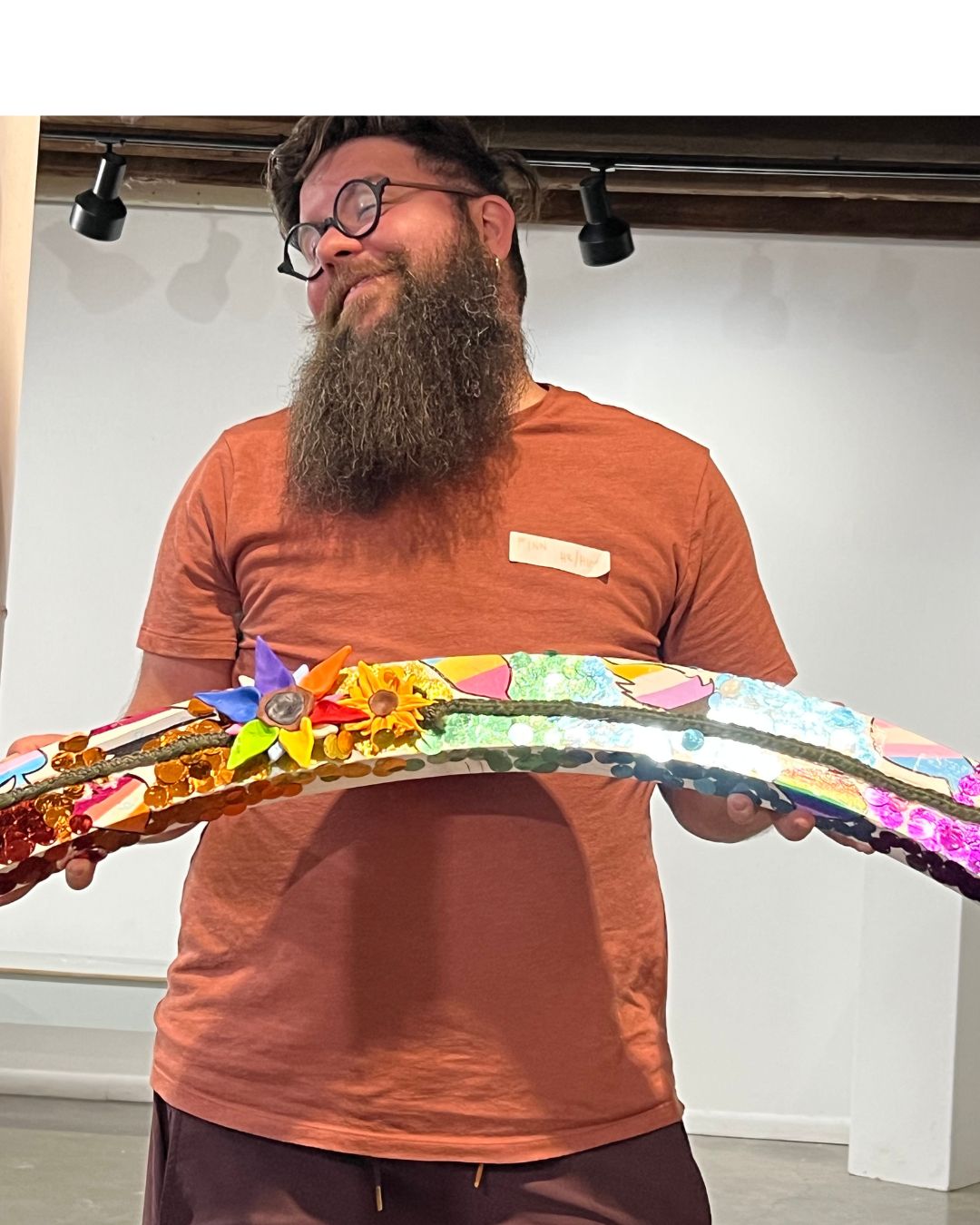 A man standing holding a piece of artwork in front of him and smiling.