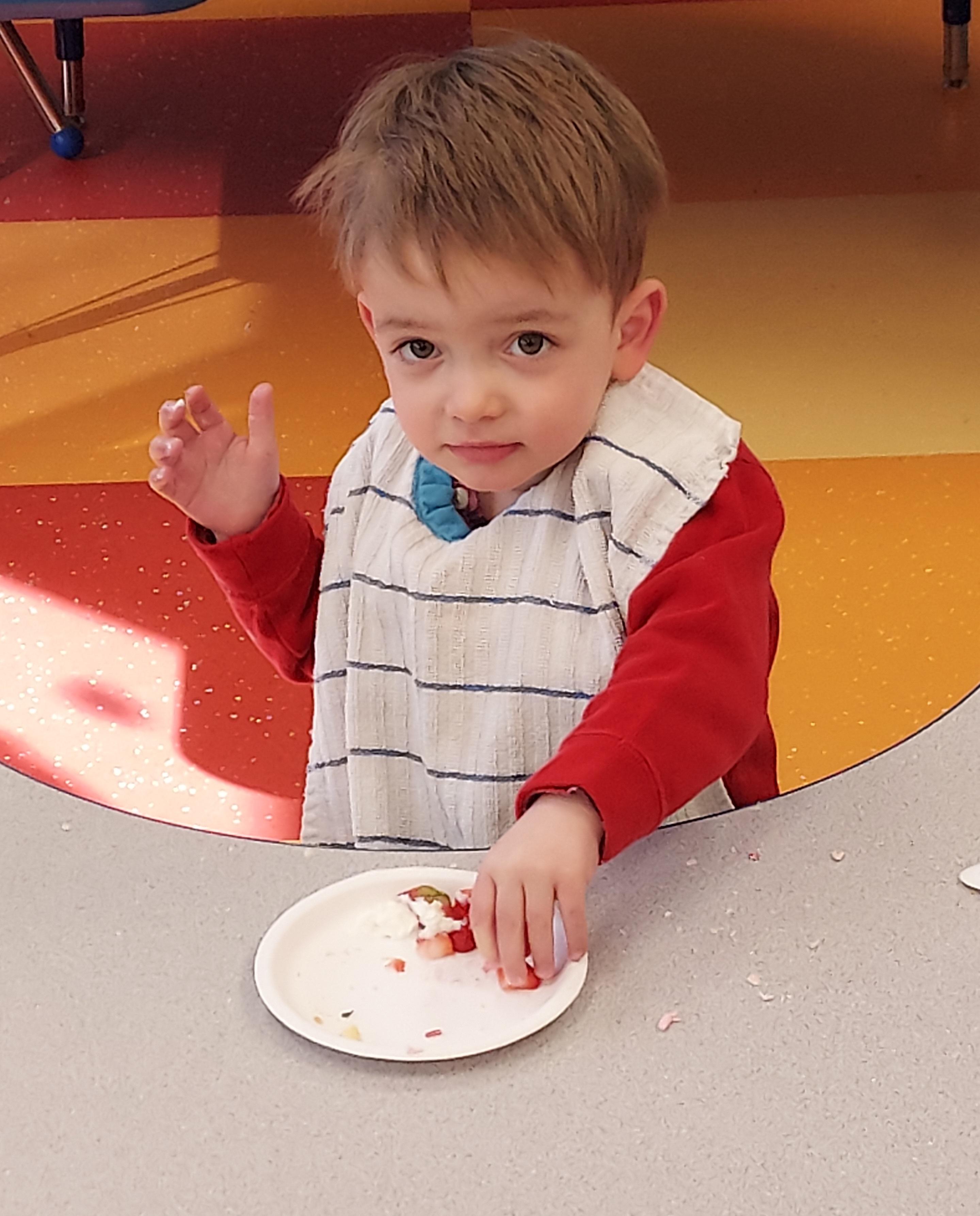 Roosevelt standing at a grey table eating strawberry shortcake.