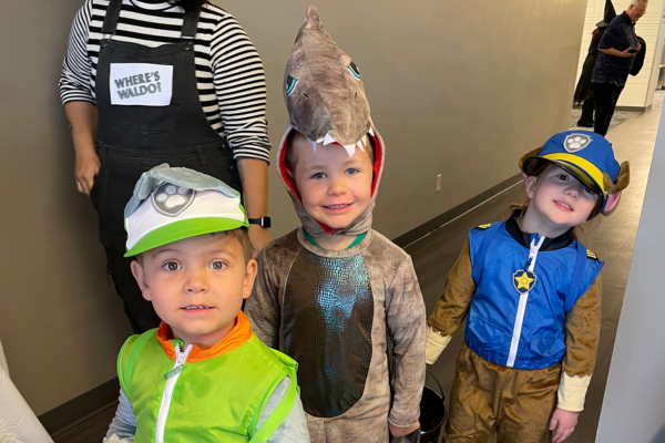 Three boys in a paw patrol, dinosaur and firefighter costume.