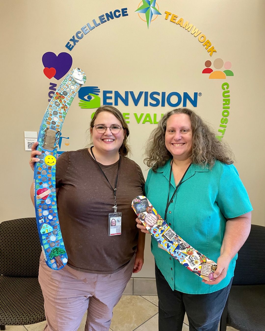 Two employees standing together with a piece of artwork, smiling.