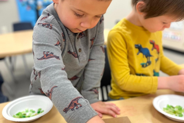 Two young boys placing jewels on their designs.