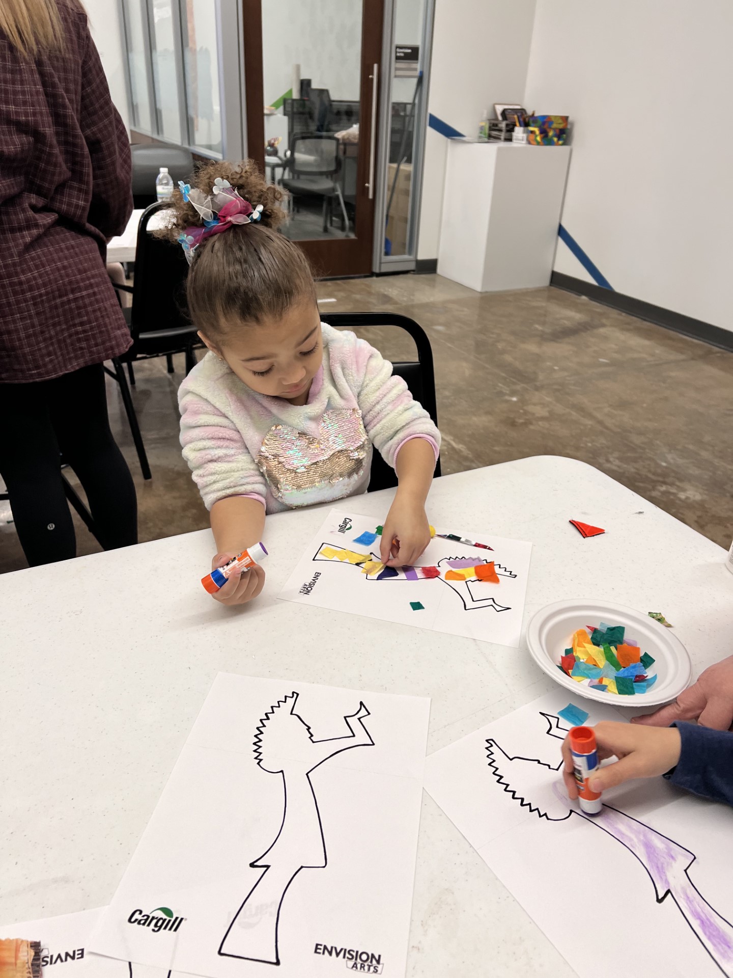A young child at an art table smiling.