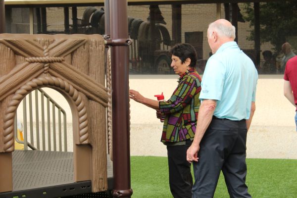 Noreen Carrocci, VP of Envision Foundation and Sam Hudson a donor, both looking at one of the pieces on the playground.