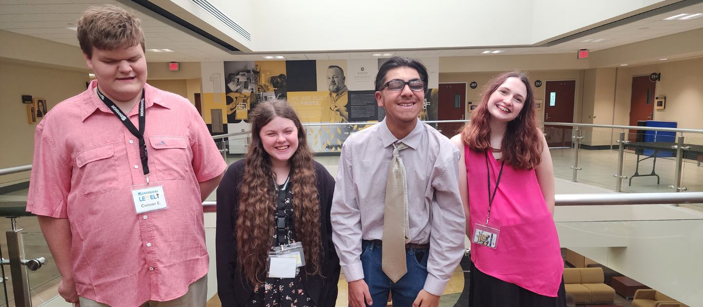 Four students standing together smiling.