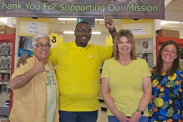 A store manager smiling with two representatives for a photo.