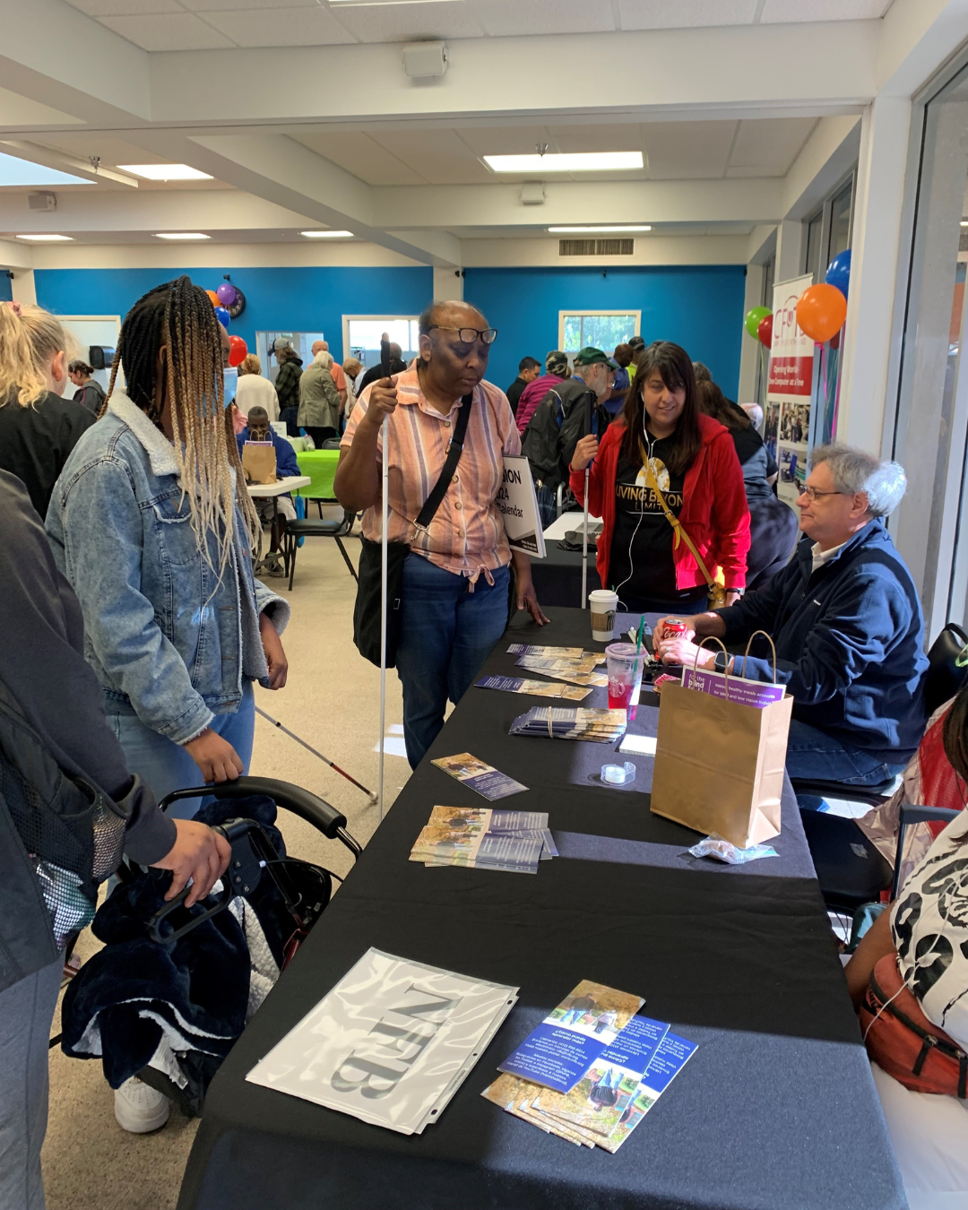 A group of people around tables with BVI organizations behind each one.