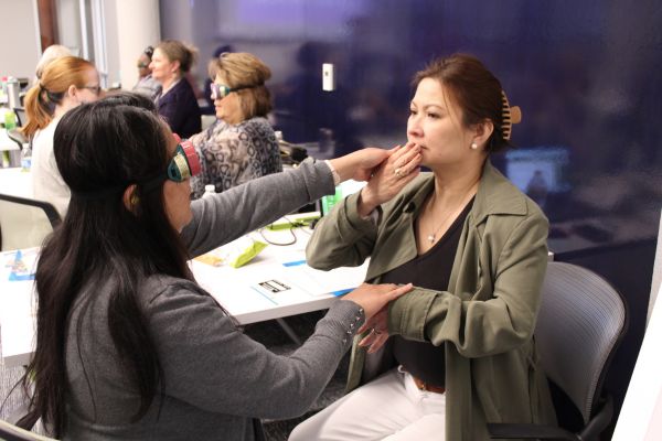 Two women learning together, one with simulator glasses on and one learning sign language.