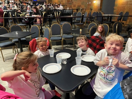 Children sitting down at the table waiting for pizza