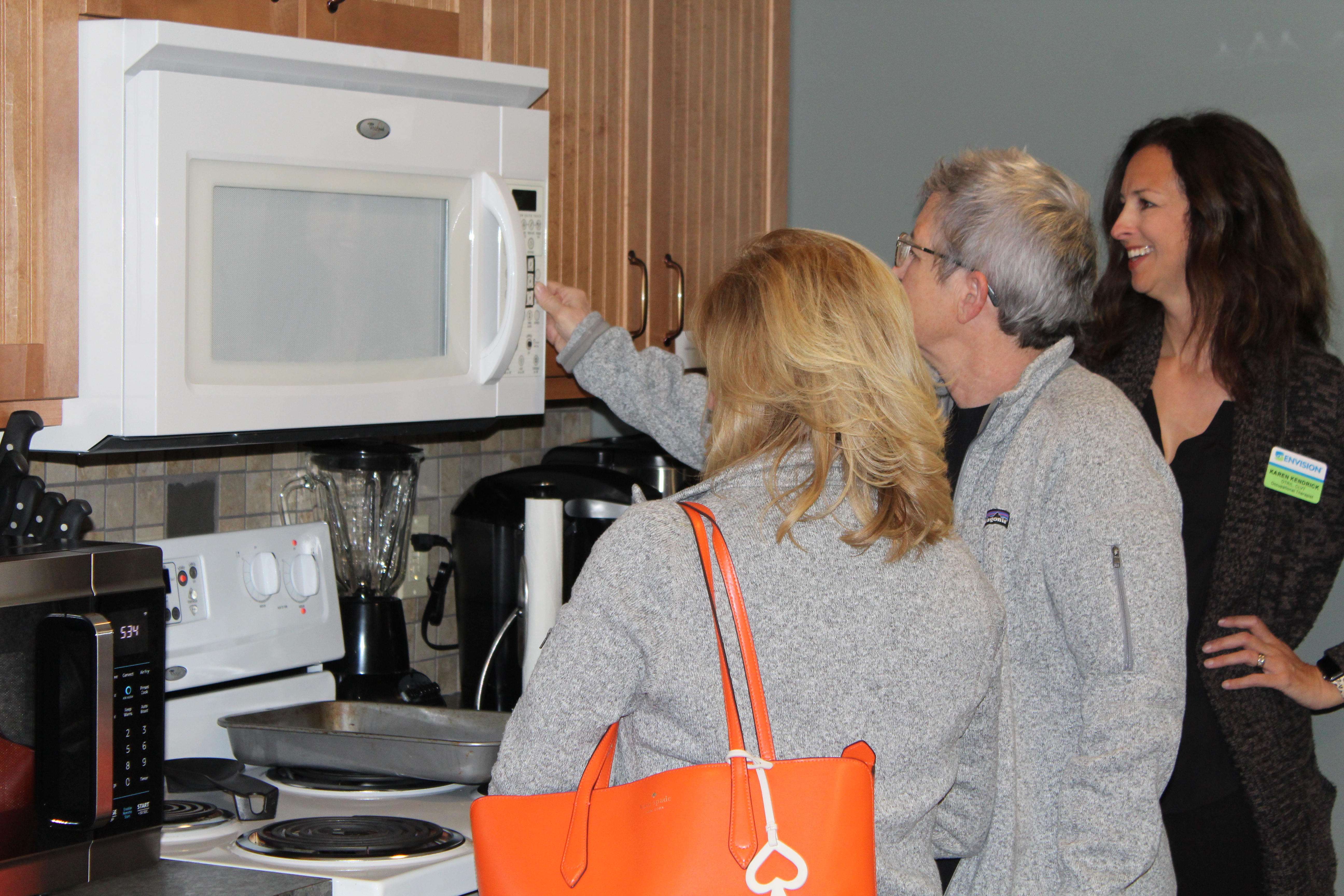 Envision Occupational Therapist shows Grand Rounds guests the accessibility of the microwave in the EVRC kitchen