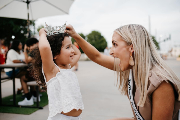 Courtney placing her crown on a young girl's head.