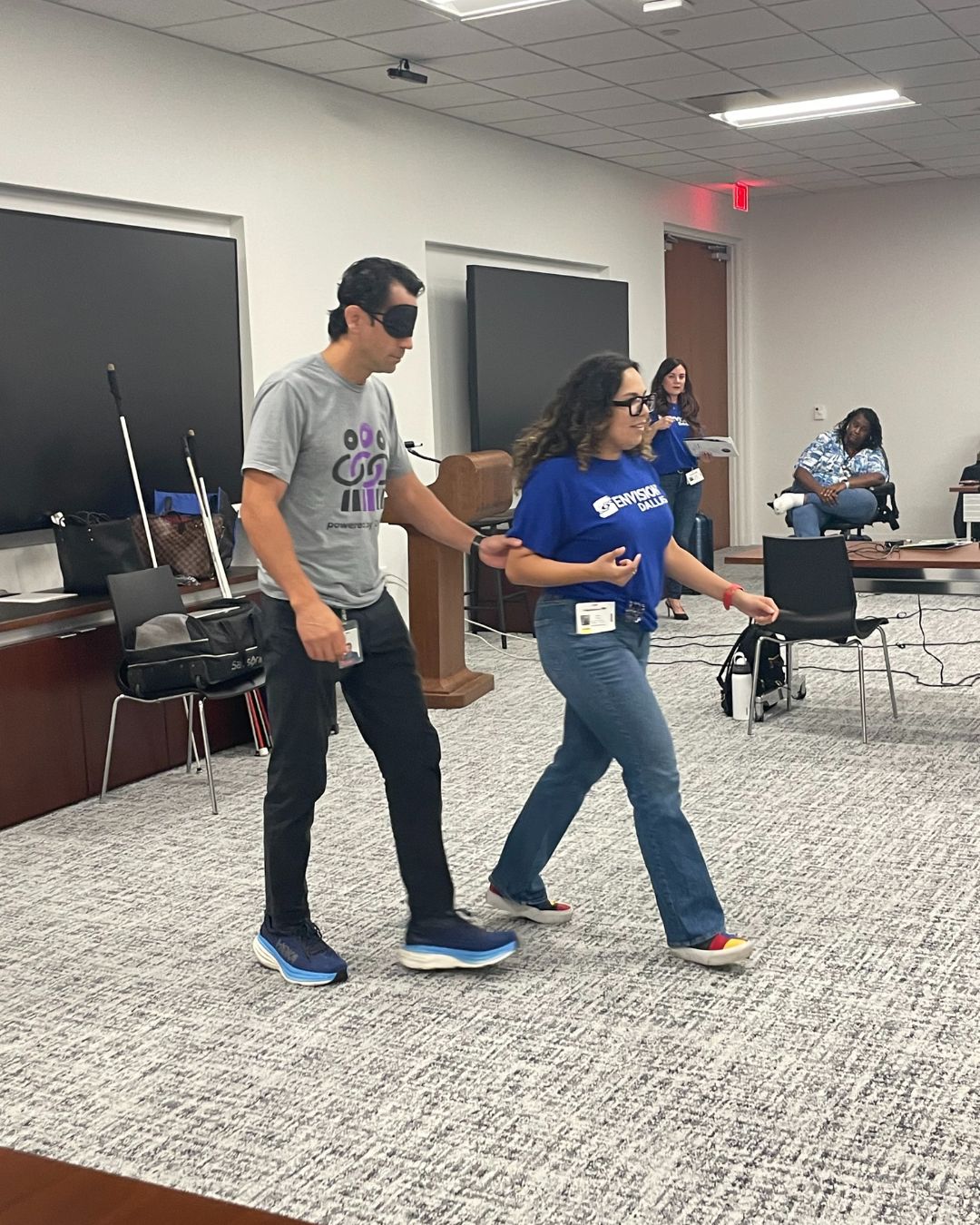 Orientation and mobility specialist guiding a sighted person who is wearing a blindfold.