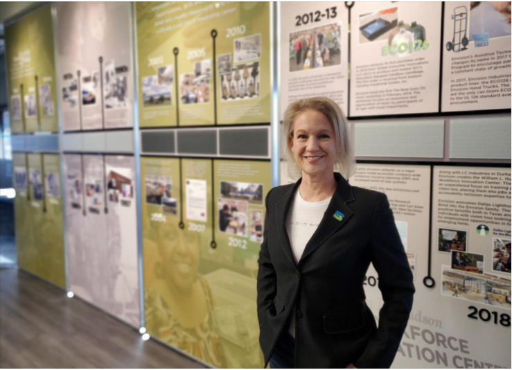 Karyn Page stands in front of a timeline wall in Envision's Workforce Innovation Center