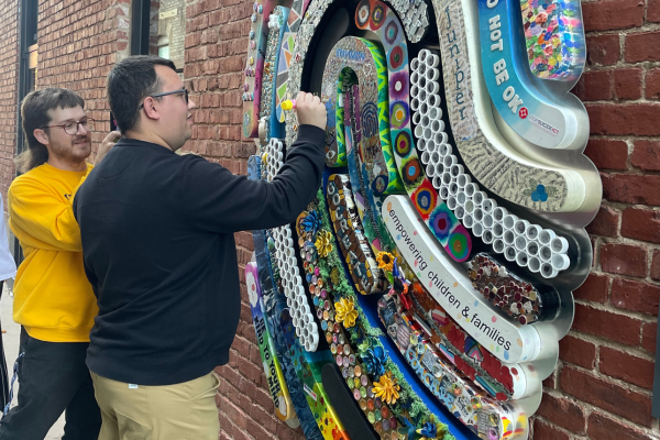 Envision Arts Gallery and Downtown Wichita Hold Opening Reception for New Community Art Piece Two men writing in chalk on the fingerprint design.
