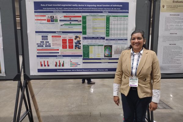 Sarika standing next to her poster on augmented reality, smiling at the camera.