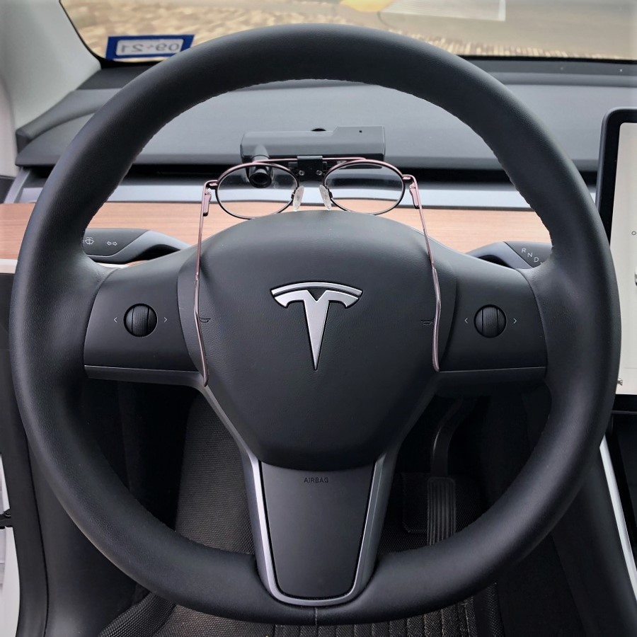 Glasses sitting on top of a Tesla car steering wheel