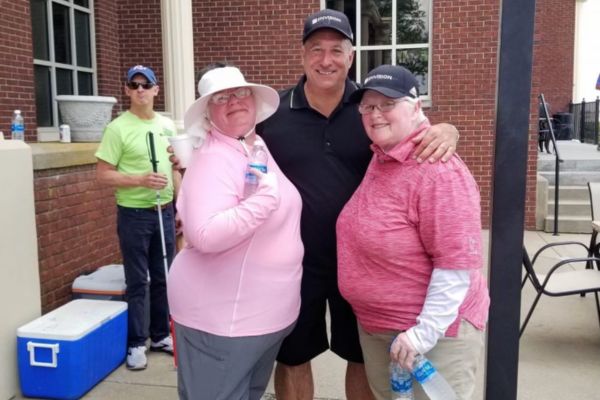 Wanda standing with Regina Henderson and Michael Monteferrante, at the 2023 Envision golf tournament.
