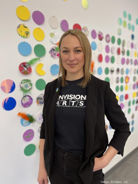 Sarah Kephart standing in front of braille art wall in Envision Arts Gallery.