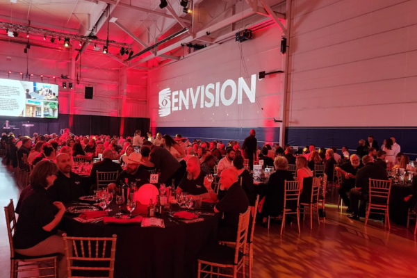 A room full of people with red LED lighting and an Envision logo on a screen.