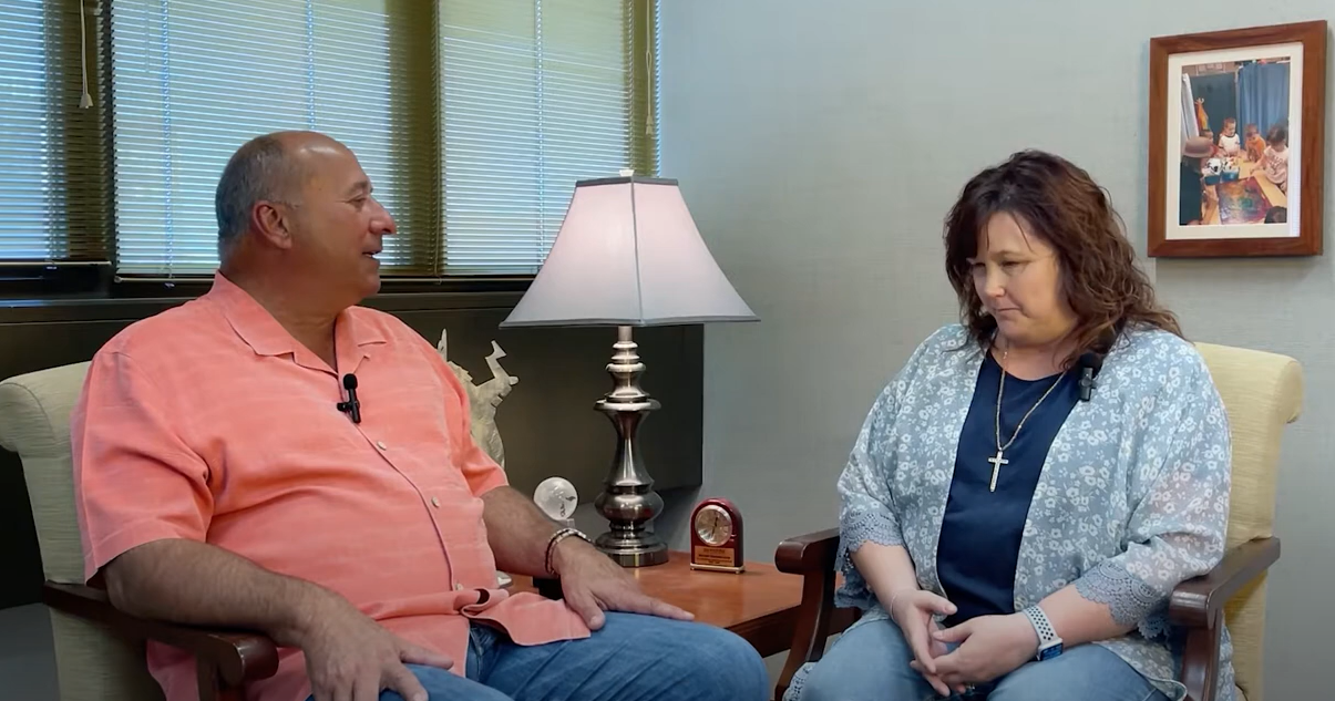 Terese Goren sitting in a chair as she talks to Michael Monteferrante, President and CEO.