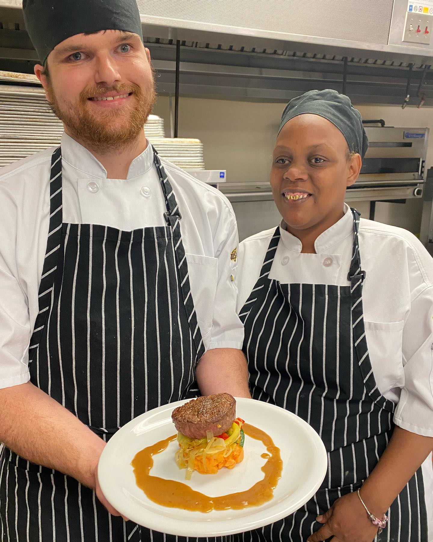 Charlie and Deyounka are in their chef aprons and hats cooking a filet mignon dish in the WSU Tech NICHE culinary arts class