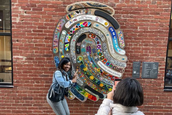 A lady pointing and smiling in front of the fingerprint,