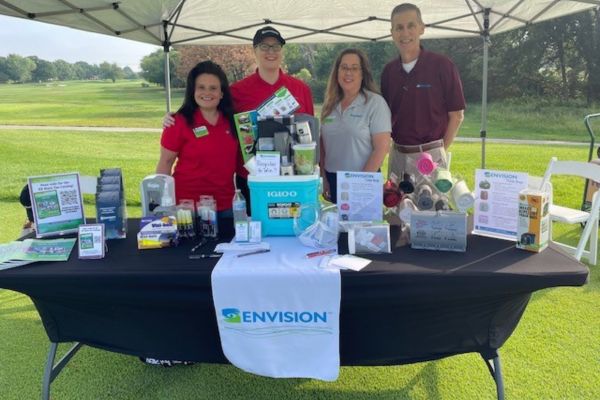 Kathy vines at the Envision booth with 3 other employees as hole 1.