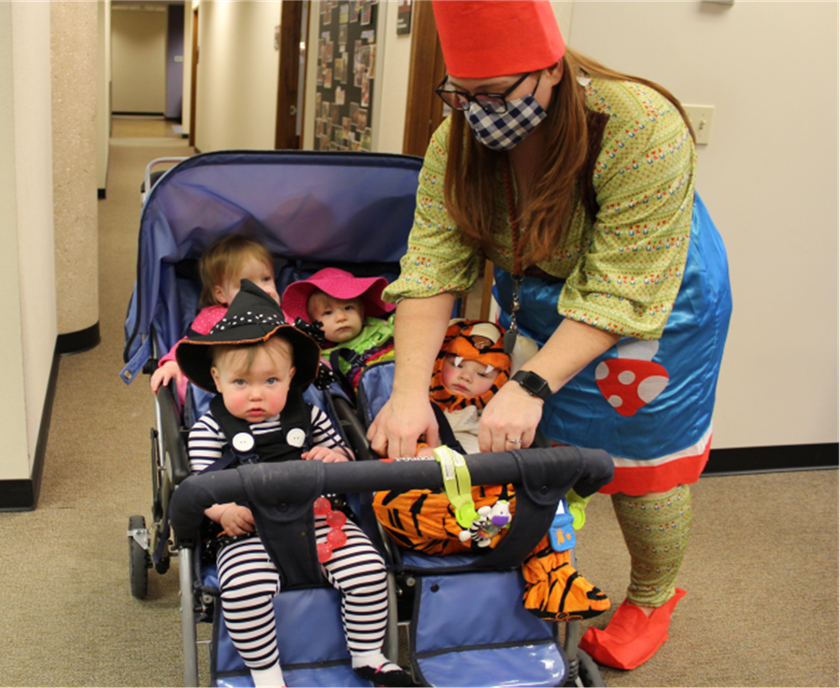 Sarah Kaehler, Early Childhood Educator in the Nursery, and four of their babies, parading on the 4th floor.