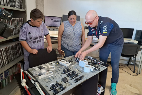 Inspiring Progress: Paco Padilla’s Path of Giving Paco showing two people a table full of low vision technology.
