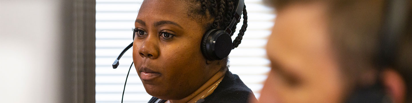 A woman wearing a headset, working on a computer.