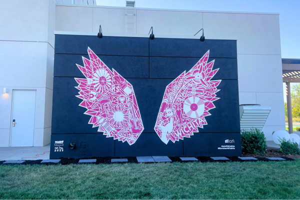 A wide view of the mural showing two pink wings with a variety of symbols in white within each wing.