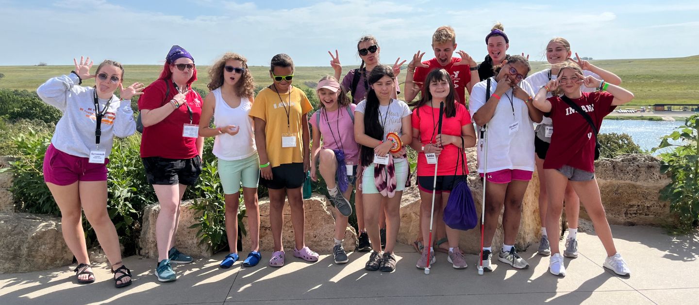 A group picture of 10 girls and their counselor smiling for the camera and making funny faces.