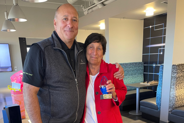 Senior VP of Foundation and Mission Services Retires Michael standing with Noreen, as she holds a karg statue that says "thank you for your service."