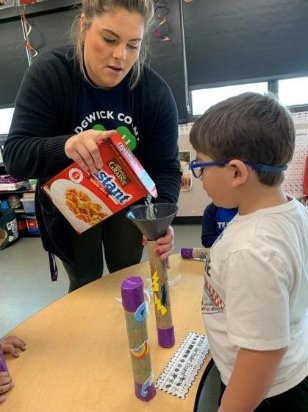 4H staff member shows pre-k how to make rain sticks