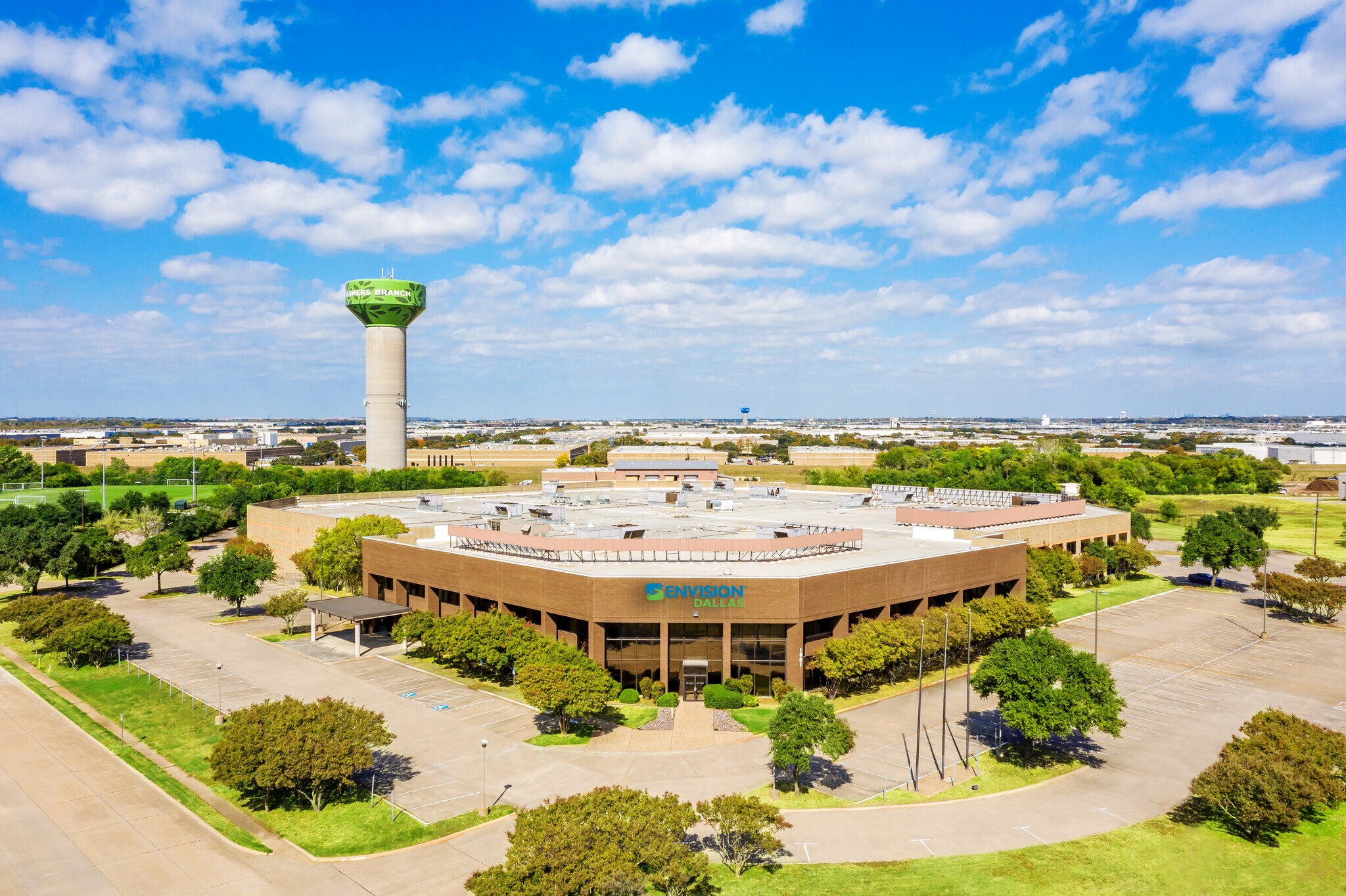 Wide shot of new Envision Dallas building in Farmers Branch with water tower in the background and blue skies and fluffy coulds