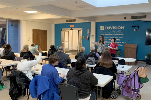 Envision Dallas Reaches More People with Expanded Programs A classroom with about 15 people sitting at desks, listening to a lecture by a Bank of America emplo
