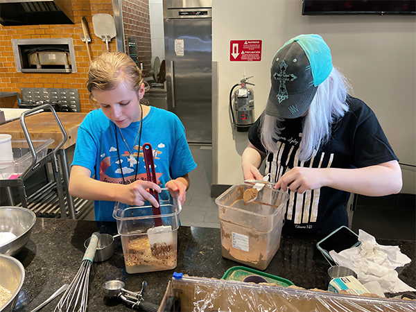 Two female BVI students at Level Up in culinary class putting together a baking recipe behind a kitchen at WSU