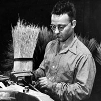 Man who is visually impaired builds a broom at the Wichita Workshop for the US Army during WWII.