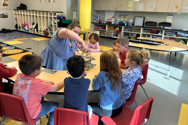Creative Exploration at the Envision Child Development Center Sophia with 4H using shaving cream in a science experiment while children watch.
