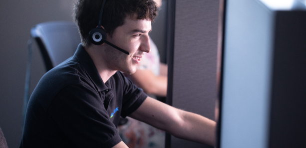 Young man who is blind chats with a customer at the Innovation Workforce Call Center.