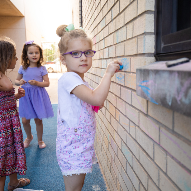 Girls play with chalk in the playground at the Envision Childhood Development Center.
