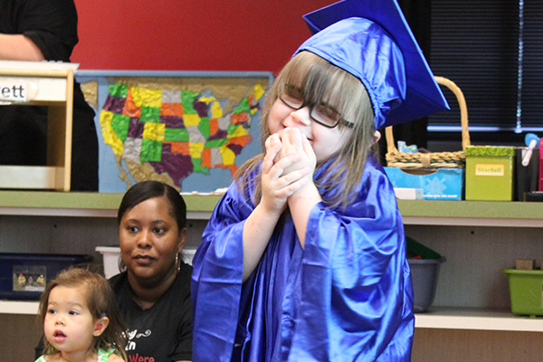 Young girl who is blind or visually impaired smiling while wearing a graduate cap and gown